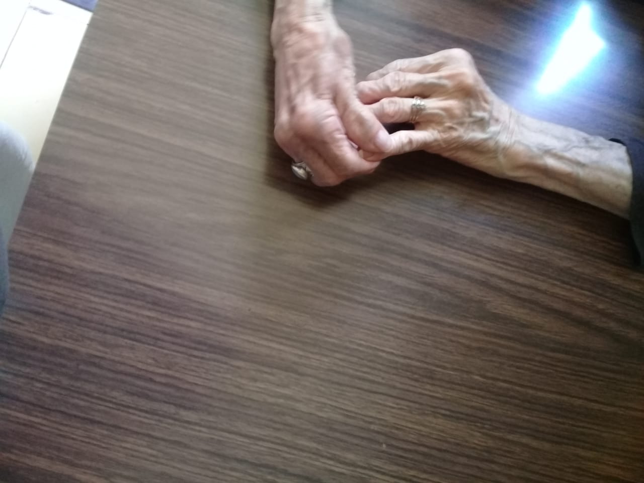 The weathered hands of an elderly woman resting together
