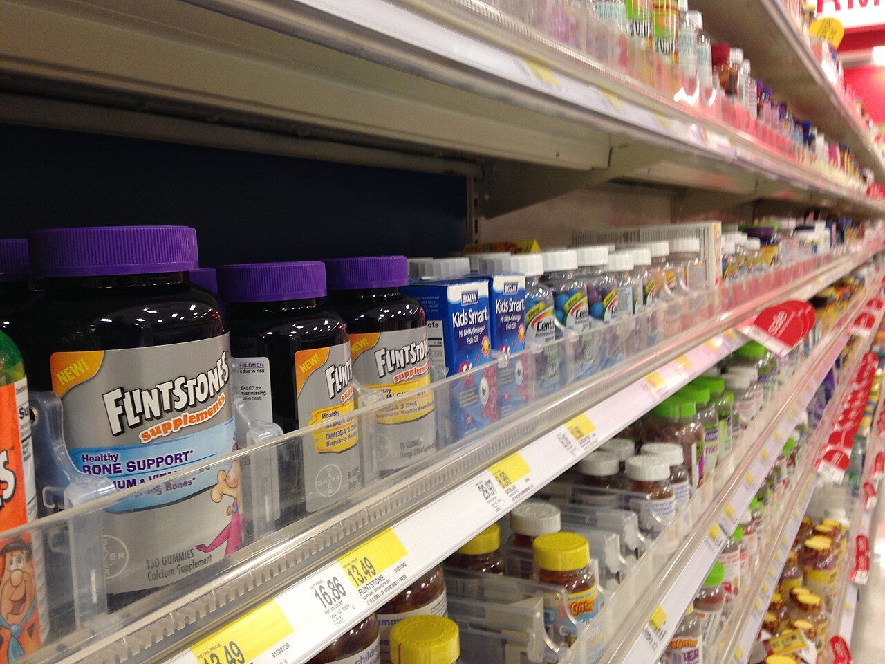 Retail display shelves stocked with vitamin and dietary supplement bottles