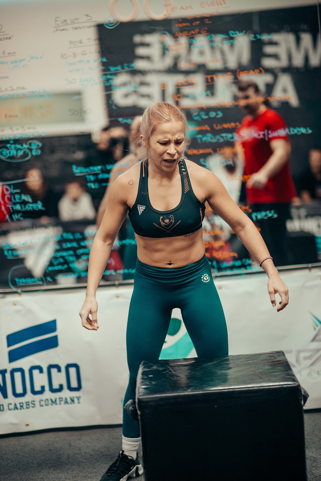 An athlete performing an explosive box jump during a fitness competition