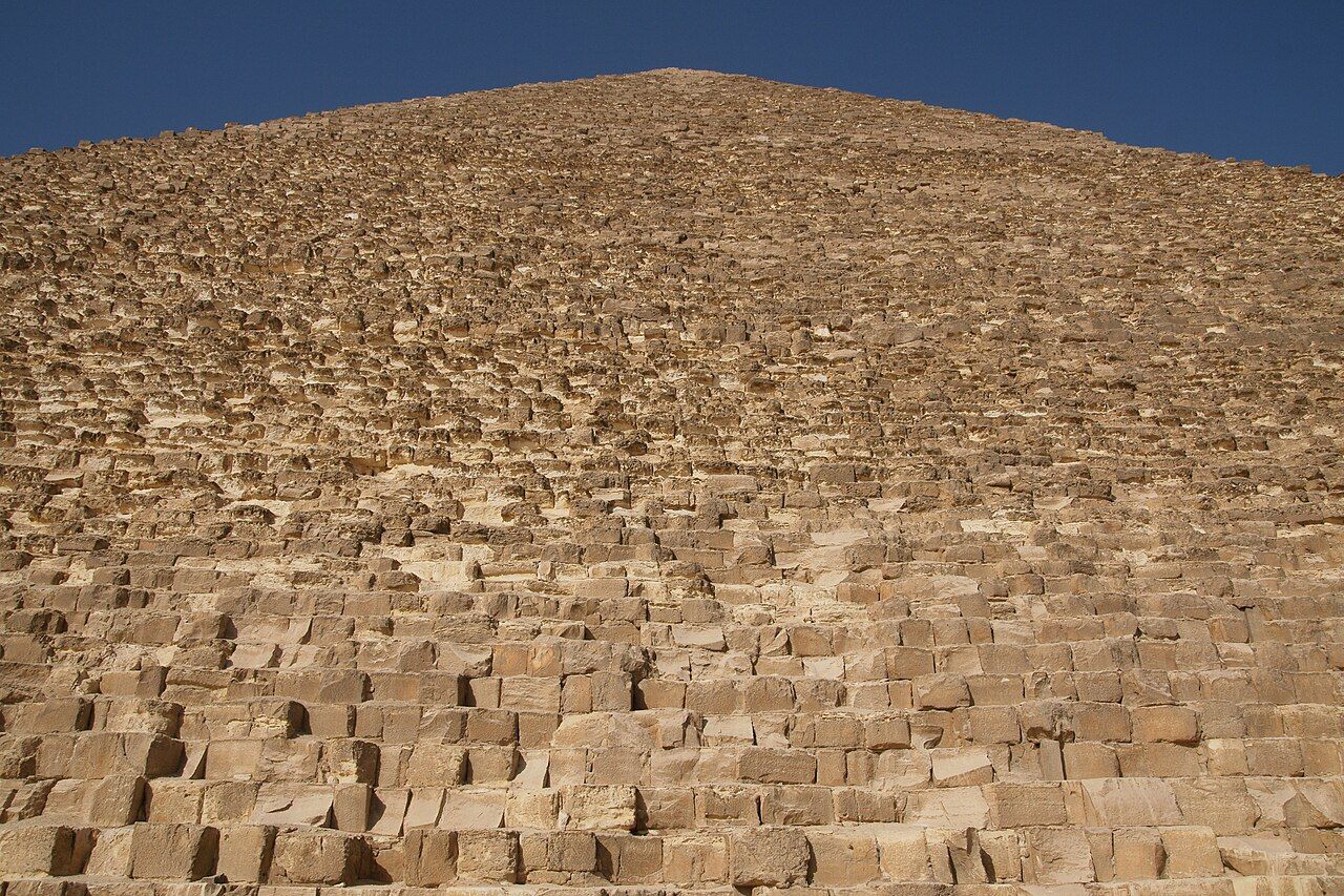The three great pyramids of Giza rising above the desert plateau, with the largest, the pyramid of Khufu, dominating the skyline under a clear sky